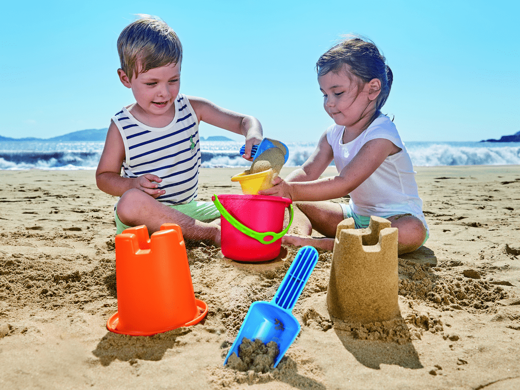 Kind spielt mit Hape Strandset am Strand
