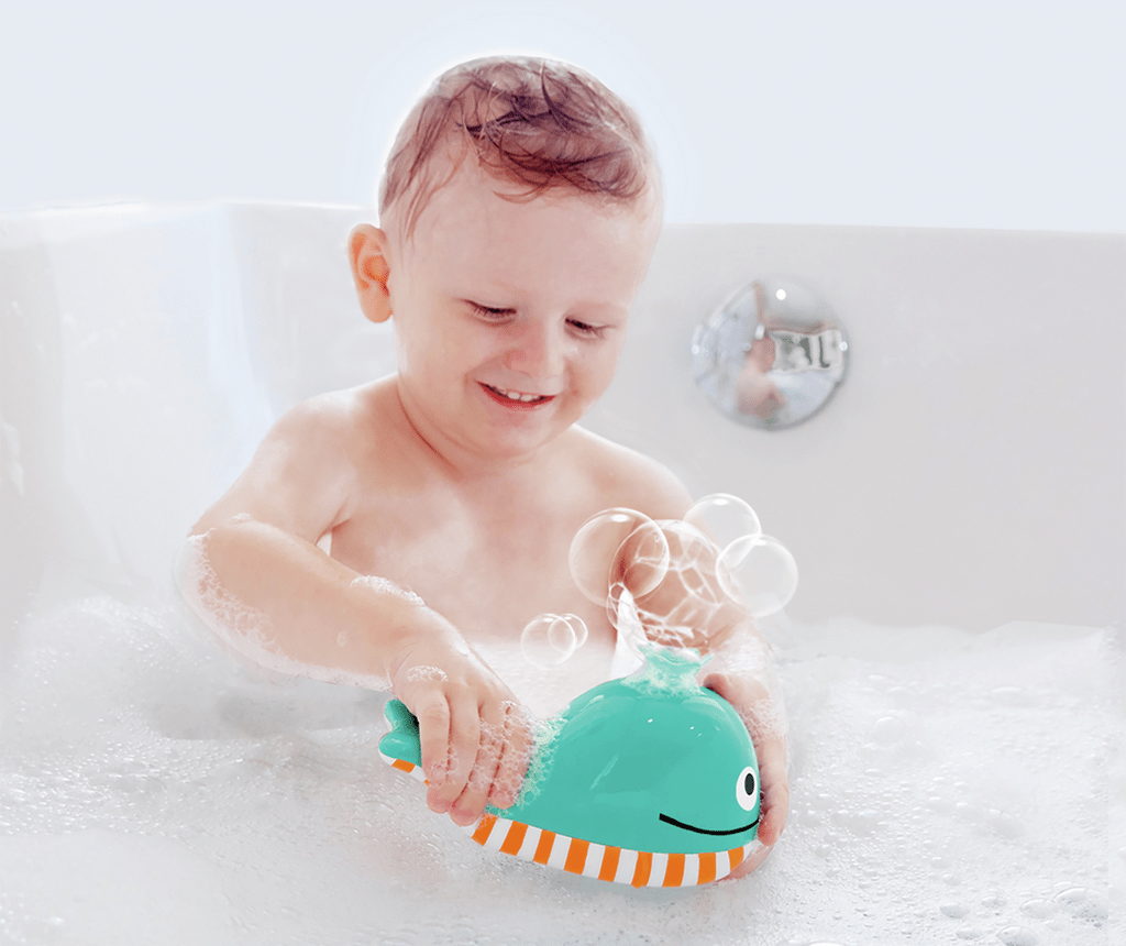 Kleinkind spielt mit Seifenblasen-Wal in der Badewanne