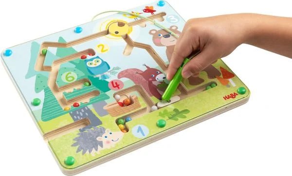 Kind spielt Magnetspiel Waldfreunde und sortiert Kugeln nach Farben
