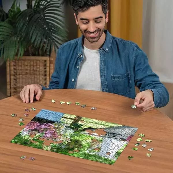 Person puzzelt ein halbfertiges 500-Teile-Puzzle mit Blumenmotiv an einem Holztisch