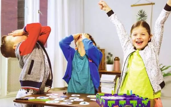 Kinder spielen GlibberKlatsch mit klebrigen Händen und Monsterkarten
