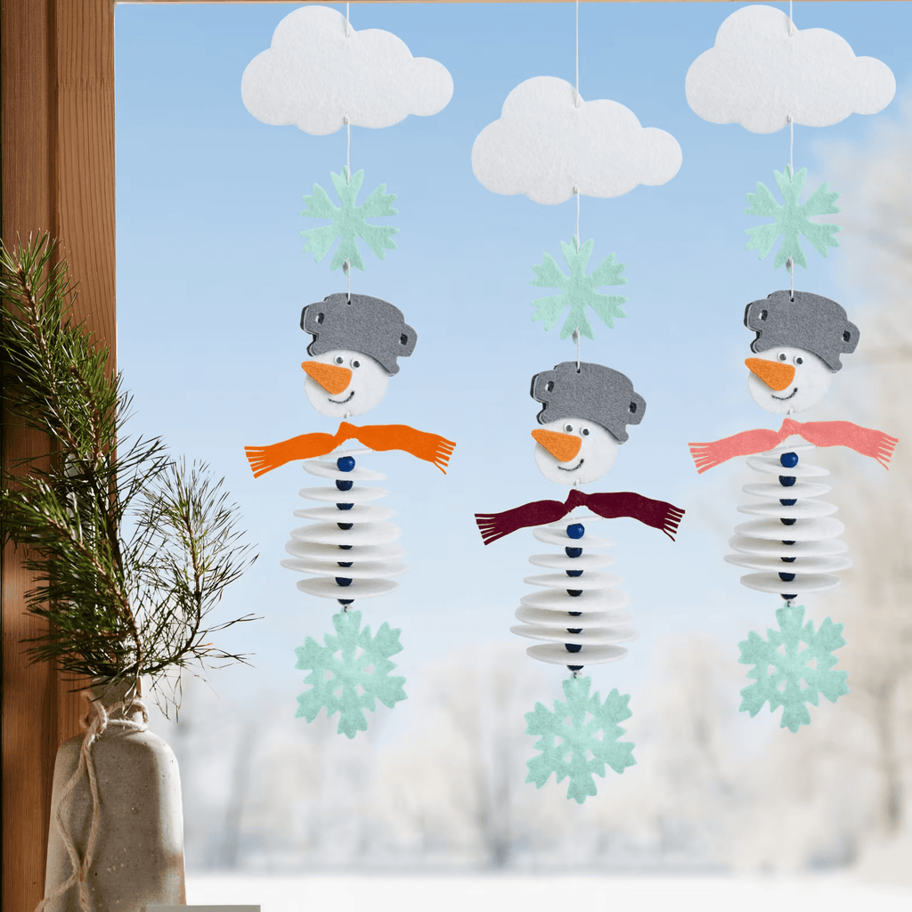 Drei fertig aufgefädelte Schneemänner als Girlande mit Stickgarn und Kunststoffnadel dekorativ am Fenster angebracht