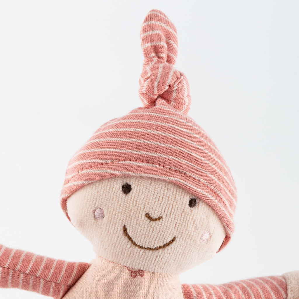 Baby hält Sigikid Rasselpuppe – erstes Kuschelspielzeug
